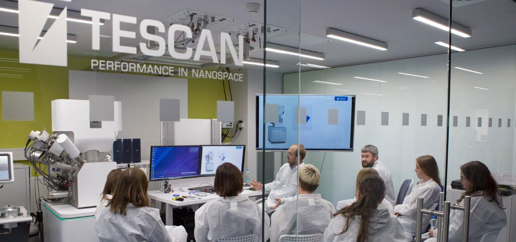 Grupo de profesionales participando en una capacitación práctica sobre microscopía electrónica en el laboratorio demostrativo de TESCAN, enfocados en el uso de tecnología avanzada para caracterización de materiales.